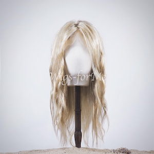 Könnte beinhalten: Eine lange, wellige, blonde Perücke auf einem Mannequin-Kopf. Die Perücke ist in lockeren Wellen gestylt und hat eine natürlich aussehende Farbe.