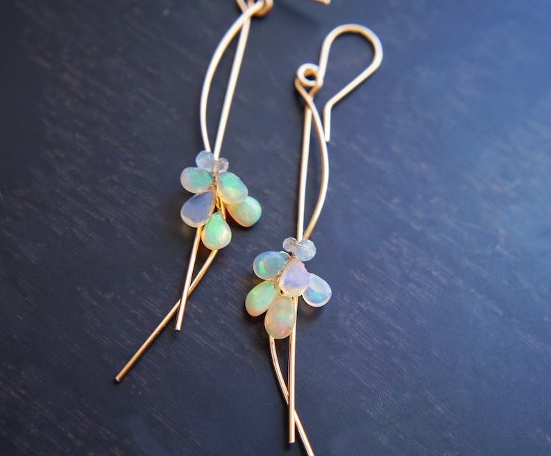 These earrings features iridescent ethiopian opal smooth drops are wire wrapped with wavy wire. These unique earrings add a touch of feminine charm to just about any outfit.