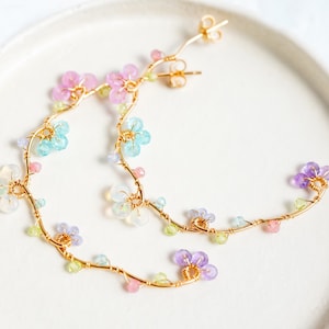 Pastel color gemstone beads such as topaz, opal, tanzanite and amethyst.. are formed into small flowers on vine hoop.