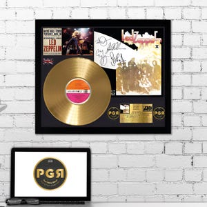 Könnte beinhalten: Eine goldene Schallplatten-Auszeichnung mit schwarzem Rahmen. Die Plakette zeigt eine goldene Schallplatte, ein Schwarzweißfoto einer Band und eine Unterschrift. Der Text "Led Zeppelin II" ist auf der Plakette sichtbar. Der Text "2001" und "Platinum & Gold Records Company" ist auf der Plakette sichtbar.