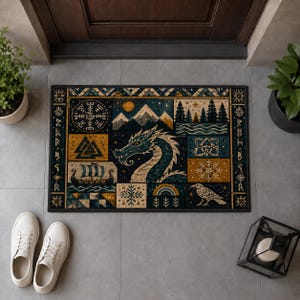 Könnte beinhalten: Eine rechteckige Fußmatte mit einem zentralen blauen Drachen, umgeben von verschiedenen Feldern, die ein Wikingerschiff, einen Kompass, Berge, einen Wald, einen Raben und geometrische Muster in Blau-, Gold- und Cremetönen mit dunklem Rand zeigen.