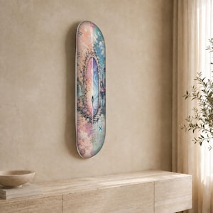 May include: A skateboard deck featuring a vertical, ornate mirror graphic that depicts a split scene of a pastel-coloured landscape and a dark, starry sky. A small figure stands before the mirror, surrounded by floral details and celestial motifs.