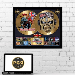 Könnte beinhalten: Eine gerahmte Doppel-Gold-Platte für Iron Maiden. Die Platte ist in einem schwarzen Rahmen mit goldener Umrandung. Die Platte ist in zwei Abschnitte unterteilt, jeder mit einem anderen Bild. Die linke Seite zeigt ein rotes und schwarzes Bild von Eddie, dem Maskottchen der Band, auf einem Pferd reitend. Die rechte Seite zeigt eine Nahaufnahme von Eddies Gesicht mit einem Pilotenhelm und einer Schutzbrille. Die Platte ist von einem schwarzen Rand mit den in Gold gedruckten Worten "Iron Maiden" und "Special Edition" umgeben. Die Platte ist auch von einem kleineren schwarzen Rand mit den in Gold gedruckten Worten "Platinum & Gold Records Company" umgeben.