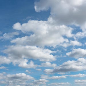 Può includere: Un cielo azzurro brillante pieno di soffici nuvole bianche. Le nuvole variano per dimensioni e forma, creando una composizione dinamica e ariosa. L'immagine cattura una giornata di sole con un'atmosfera limpida.