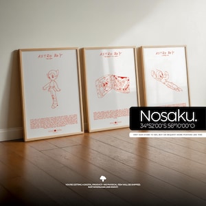May include: Three framed Astro Boy art prints. Each print features a red illustration of Astro Boy on a white background. The frames are light brown. The prints are displayed on a wooden floor.