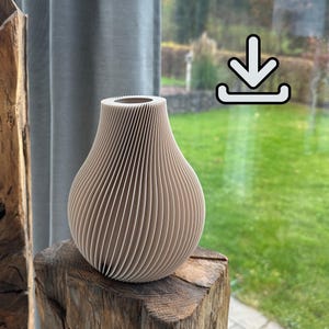Könnte beinhalten: Eine beige, gerippte Vase in Tropfenform, die auf einem Holzblock steht. Die Vase hat eine breite Öffnung und vertikale Linien, die eine strukturierte Oberfläche erzeugen. Der Hintergrund zeigt ein Fenster mit einem grünen Rasen und einem grauen Vorhang.