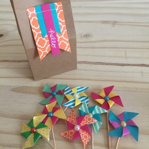 May include: A brown paper gift bag with a bright orange, teal, and pink patterned tag that says 