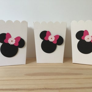 May include: Three white favor boxes with scalloped edges, each decorated with a black silhouette of Minnie Mouse's head with a pink bow and a white flower.
