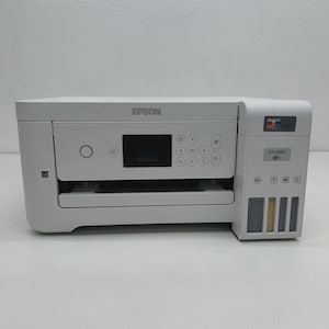 May include: A white Epson ET-2850 all-in-one printer. The printer features a small display screen, control buttons, and ink tanks. The Epson logo is visible on the top. The printer is on a white surface.