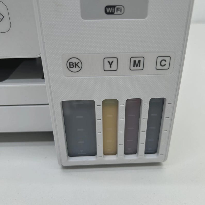 May include: A close-up of a white printer showing ink tanks and control buttons. The printer has a Wi-Fi symbol and buttons labelled BK, Y, M, and C. The ink levels are visible in the tanks.