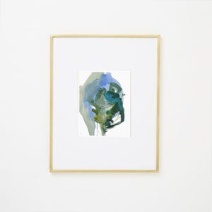 May include: Abstract watercolor painting in a gold frame. The artwork features a blend of blue, green, and yellow brushstrokes on a white background. The gold frame adds a touch of elegance to the piece.
