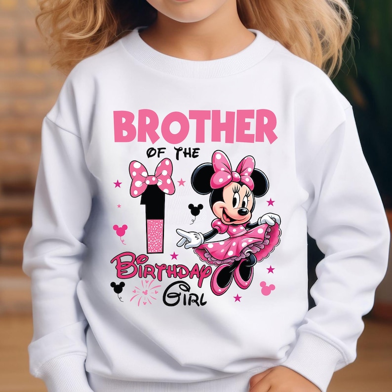 May include: White sweatshirt with a pink Minnie Mouse graphic. The design includes the text "BROTHER OF THE BIRTHDAY GIRL" and the number "1". Minnie Mouse is wearing a pink dress and bow. The design also features pink stars and bows.
