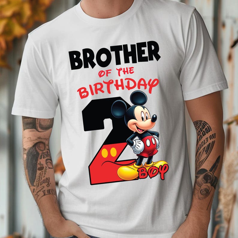 May include: White t-shirt with the text "BROTHER OF THE BIRTHDAY" in black and red. A cartoon Mickey Mouse graphic is on the shirt, along with the number 2 in red and black, and the word "BOY" in yellow.