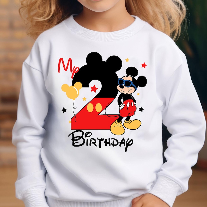 May include: White sweatshirt featuring a Mickey Mouse design for a second birthday. The design includes a large number 2, Mickey Mouse wearing sunglasses, the words "My Birthday", and star and balloon graphics.