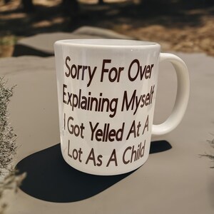 May include: White ceramic mug with brown text that reads "Sorry For Over Explaining Myself I Got Yelled At A Lot As A Child"