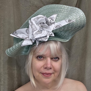 May include: A green wide-brimmed hat with a large flower made of US dollar bills.