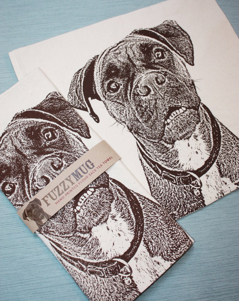 May include: Two brown and white tea towels with a black and white illustration of a boxer dog. The towels are hand printed and have the text "FuzzyMug Hand Printed Flour Sack Tea Towel" on the bottom.