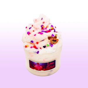 May include: A jar of white slime topped with colorful heart-shaped sprinkles and a charm. The jar has a label that reads "Love Potion" with a graphic of a potion bottle. The slime is decorated with red, purple, yellow, and green heart-shaped sprinkles.