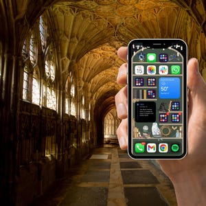 May include: A smartphone with a green background and a variety of app icons, including a weather app showing a temperature of 50 degrees. The phone is being held in a hand against a background of a stone hallway with arched ceilings and windows.