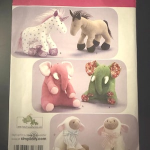 May include: A Simplicity sewing pattern envelope 2921 for stuffed animals. The front displays illustrations of a white unicorn with stars, a tan horse, a pink elephant, a green elephant with floral ears, and two white lambs with ribbons.