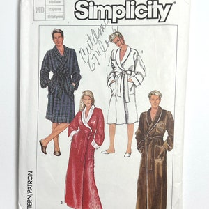 May include: Simplicity sewing pattern number 7659 for a robe. The pattern includes three different styles: a plaid robe, a red robe, and a brown robe. The pattern is for medium sizes.