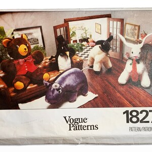 May include: A vintage Vogue Patterns sewing pattern envelope featuring a brown teddy bear, a penguin, a white sheep, a white rabbit, and a purple hippopotamus. The pattern number is 1827.
