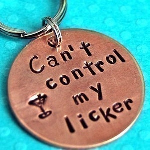 May include: A copper-colored keychain with a silver key ring. The keychain has a martini glass icon and the text "Can't control my licker".