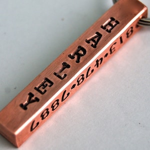 May include: A copper keychain with the text "YETI" and "888-811-E1E1" engraved on it.