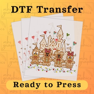 May include: A sheet of clear transfer paper with a gingerbread castle and gingerbread characters. The castle is decorated with candy canes and red and white hearts. The characters are wearing red and white bows. The text "DTF Transfer" and "Ready to Press" is printed on the sheet.