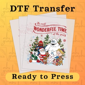 Peut inclure: Feuilles de transfert DTF avec un motif festif. Le motif présente le texte "The most WONDERFUL TIME of the year" avec des personnages de dessins animés, dont le Père Noël, un bonhomme de neige et un yéti. Les mots "Ready to Press" sont également visibles.