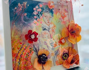 May include: A framed artwork featuring a watercolor portrait of a person with floral accents. The artwork is adorned with three-dimensional orange and red paper flowers. The frame is white, and the background is a mix of colors.