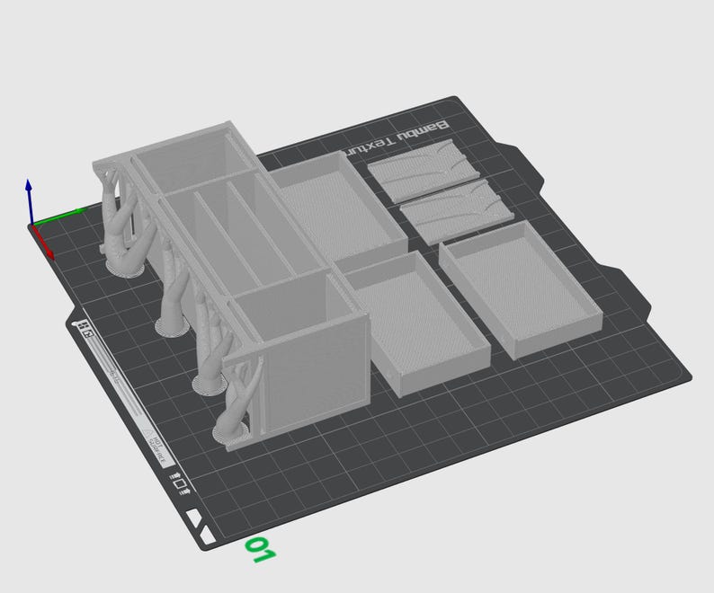 May include: A light gray 3D-printed organizer with multiple compartments and drawers. The organizer features decorative tree-like supports and is set on a textured black surface. Additional small trays and decorative elements are also included.