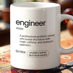 May include: White ceramic mug featuring the word "engineer" in black, accompanied by a definition. The definition describes an engineer as a professional problem solver. The mug also lists similar terms: problem solver, technical wizard.