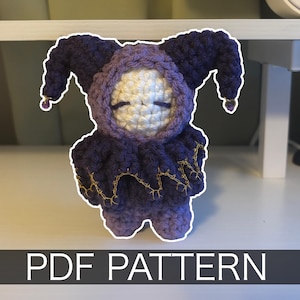 May include: A handmade crochet doll in shades of purple, with a white face and closed eyes. The doll has a hooded head with pointed ears and a ruffled collar, accented with gold thread. The text "PDF PATTERN" is displayed at the bottom.