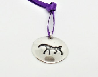 May include: A silver charm with a horse silhouette, attached to a purple ribbon.