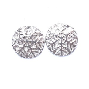 May include: A pair of silver snowflake earrings. The earrings are round and have a textured snowflake design.