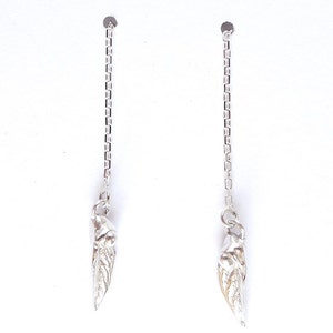 May include: A pair of silver dangle earrings with a leaf-shaped charm hanging from each chain.