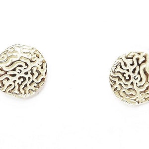 May include: A pair of silver stud earrings with a circular design featuring a raised, intricate pattern resembling a brain or coral.