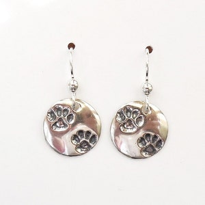 May include: Silver dangle earrings with two paw prints on each round disc.