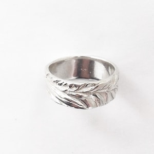 Puede incluir: Un anillo de plata con un diseño texturizado en forma de hoja.