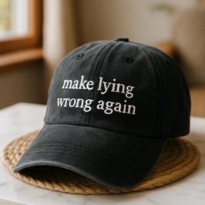 May include: A black baseball cap with the text "make lying wrong again" embroidered in white.