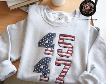 Puede incluir: Sudadera gris con los números 45 y 47 bordados en rojo, blanco y azul, que se asemejan a la bandera estadounidense.