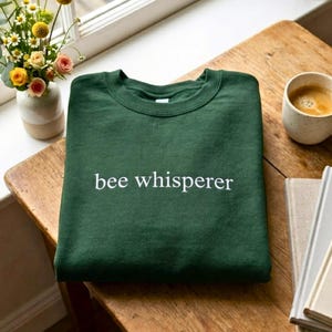 May include: A white ceramic mug with a black handle and the text "But First, Coffee" in a black, bold font. The mug is on a white surface.