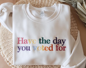 May include: White sweatshirt with the text "Have the day you voted for" embroidered in rainbow colors.