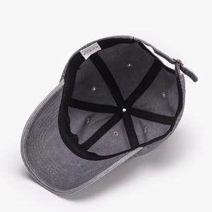 May include: A gray baseball cap with a curved brim, viewed from the inside. The cap has a black interior with a series of radiating seams. A small tag is visible inside the cap. The adjustable strap is fastened with a metal buckle.