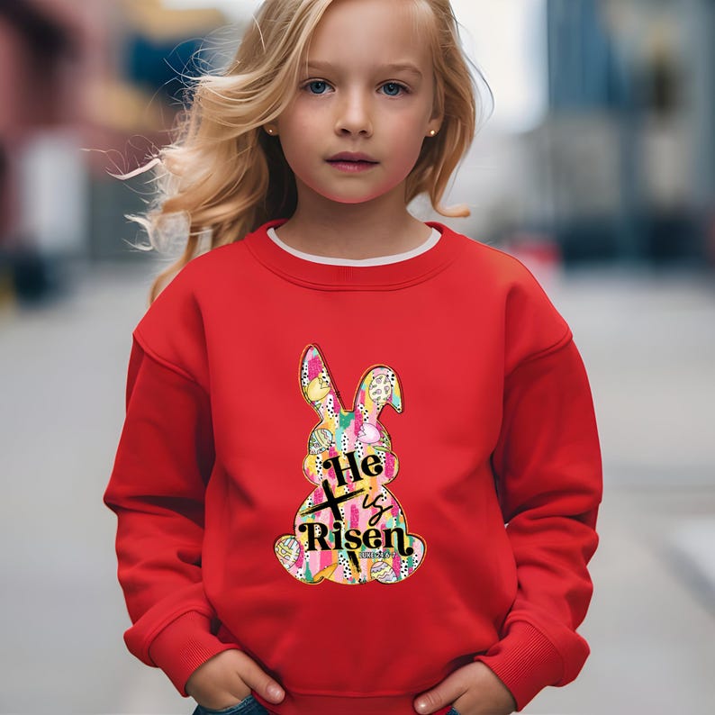 a little girl wearing a red sweatshirt with a bunny on it