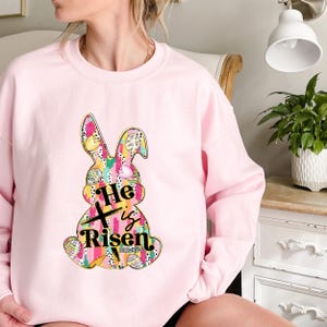 a woman sitting on a chair wearing a pink sweatshirt