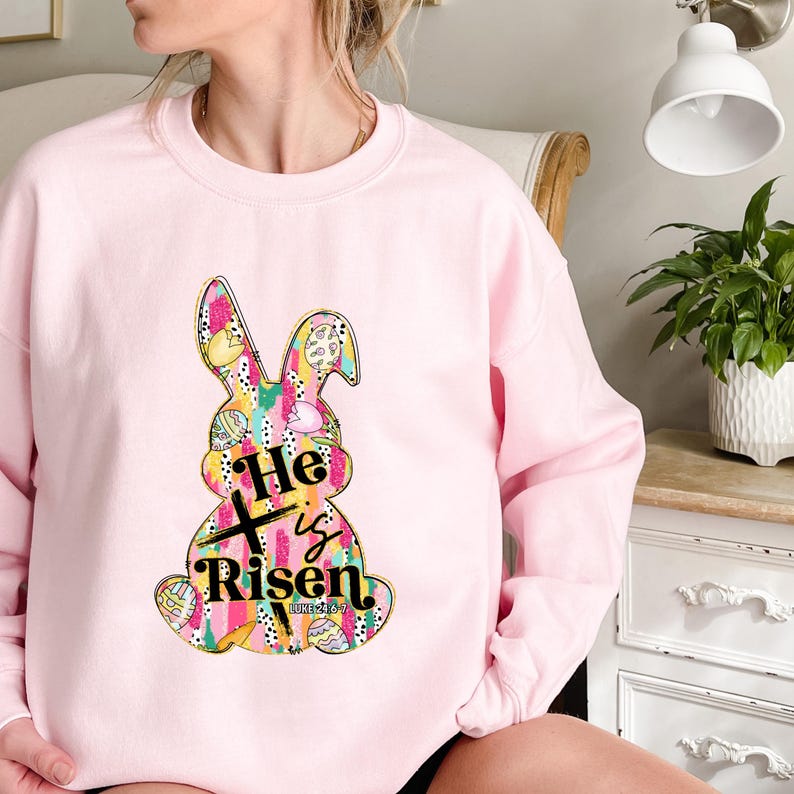 a woman sitting on a chair wearing a pink sweatshirt