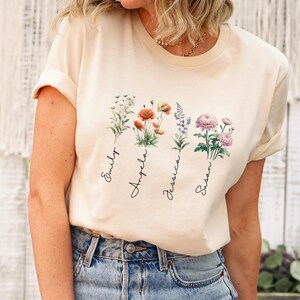 a woman sitting on a stool wearing a t - shirt with flowers on it