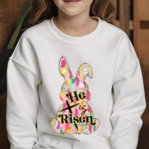 a little girl wearing a white sweatshirt with a bunny on it